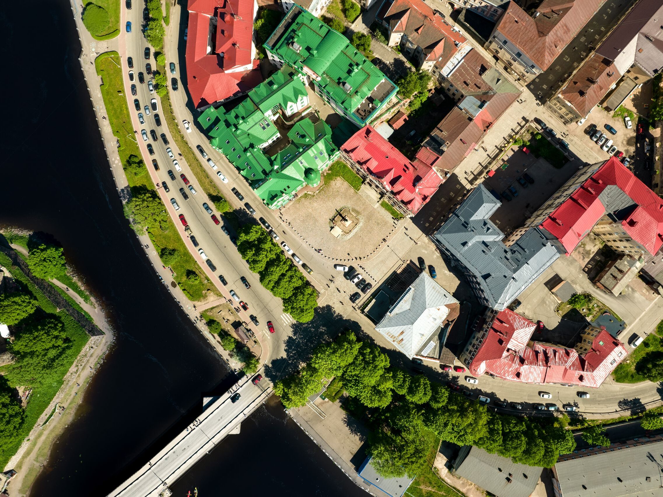 Aerial shot of a vibrant city next to a winding river, showcasing colorful rooftops and lively streets.